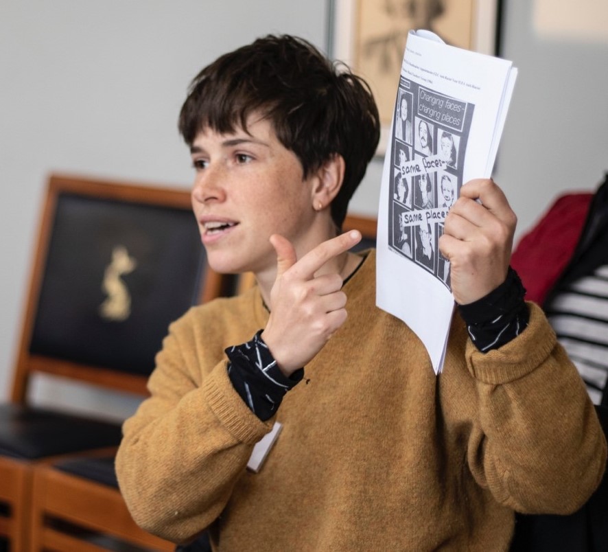 Workshop participant holding up a poster from 1984 and speaking to the room