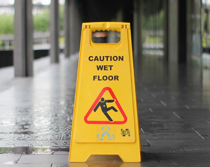 A wet floor caution sign set out on a train platform