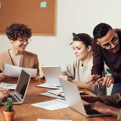 Group of people discussing work at a table with laptops