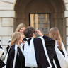Groups of students in academical dress outside the Senate House following graduation