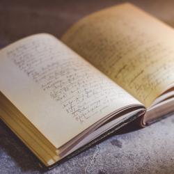 An ancient book open to a page covered in handwriting