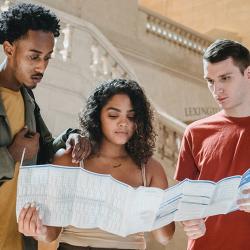 Three students poring over a timetable or map