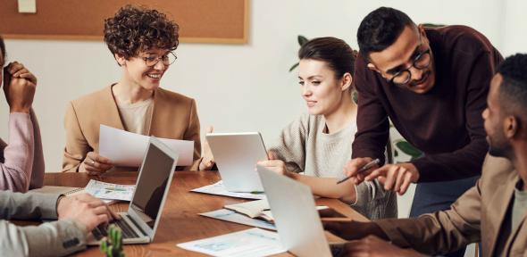 Group of people discussing work at a table with laptops