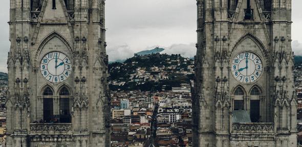Two towers flanking a church both with clocks showing different times