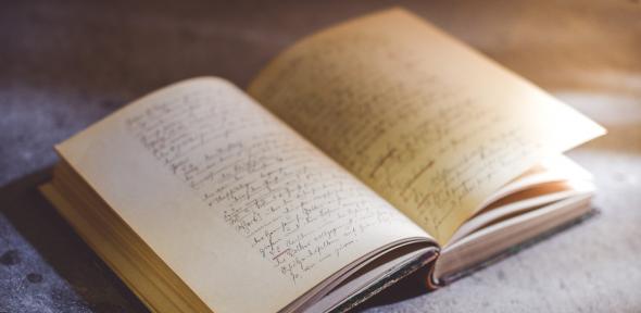 An ancient book open to a page covered in handwriting