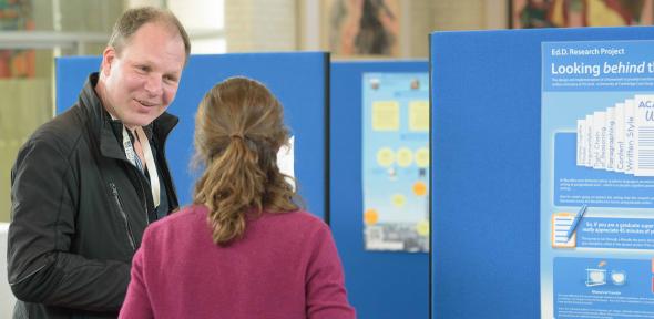 Attendees discussing a poster at the annual Cambridge Teaching Forum