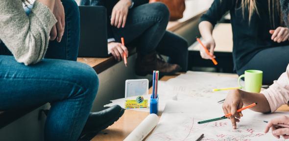 Students working on a collaborative task at a table with pens and paper