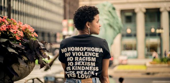 Woman wearing a shirt that says no homophobia, no violence, no racism, no sexism, yes kindness, yes peace, yes love